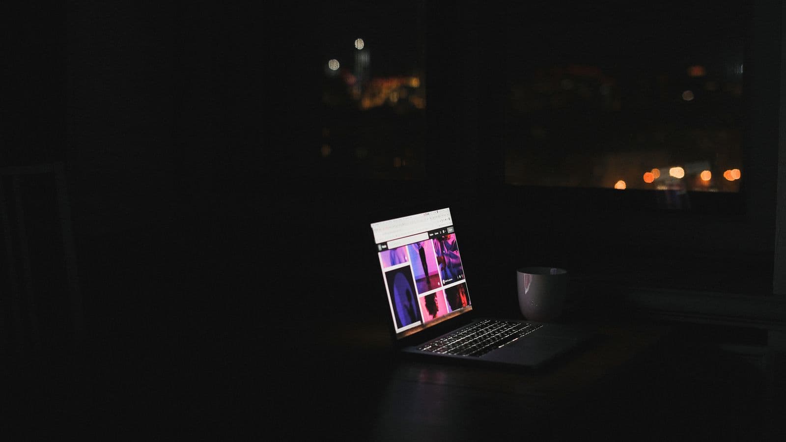 Świecący ekran laptopa z siatką kolorowych kadrów w ciemnym pokoju