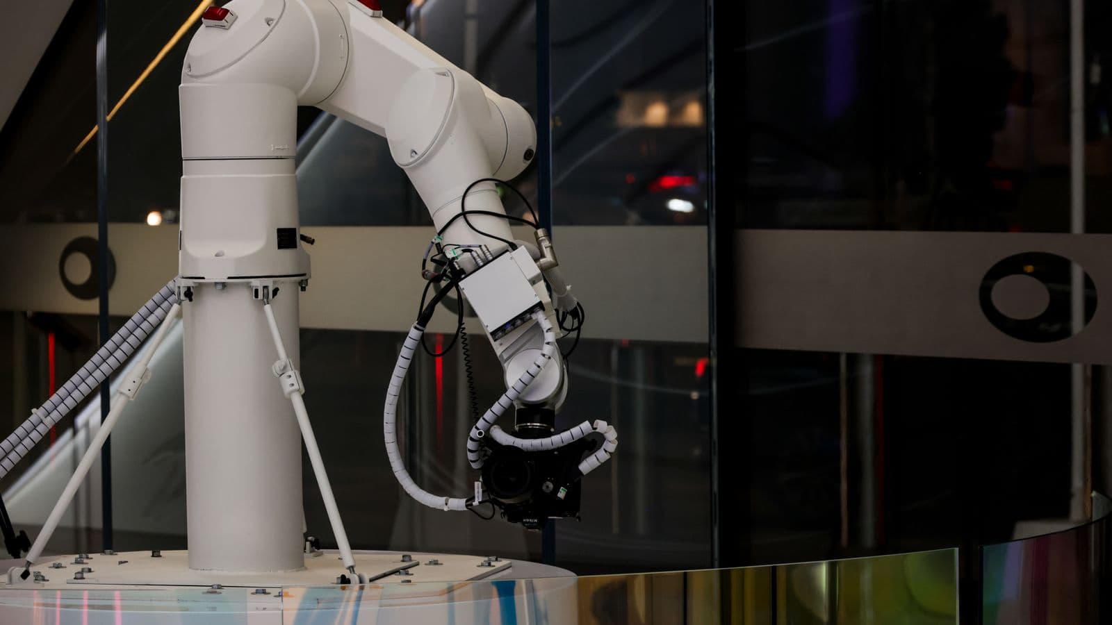 Białe ramię robota przemysłowego pracujące w ciemnej hali produkcyjnej